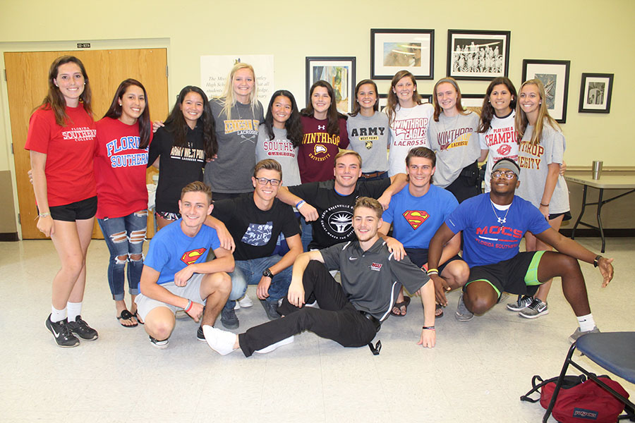 Senior athletes pose after signing their National Letter of Intent to the schools they plan to go to. Signing the letter creates a commitment between the athlete and the school, ensuring that the student will play their sport at the school they committed to.