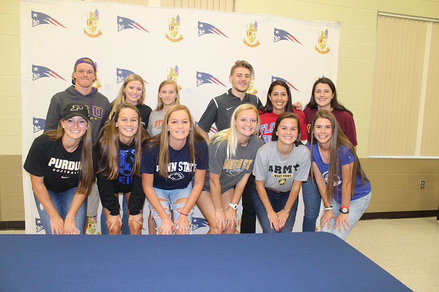 A group of Lake Brantley Athletes gather together and smile after signing the National Letter of Intent in the Community Room on Early Signing day. Family members, friends, and coaches watched as the athletes commit to where they will continue their athletics while furthering their education.