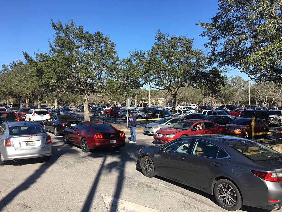 Security staff member Robert Bennet works to direct traffic in the afternoon as parents of students arrive for pick up and student drivers exit the student parking lot. “The parking lot is a chaotic mess,” sophomore Veronica Calderon said. “People are so rushed to get out so they don’t have patience for other people. That’s why Bennet has to be there; so people don’t get in an accident in their rush to leave.”