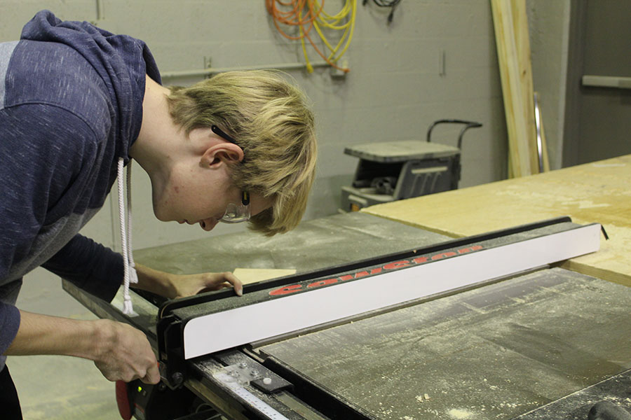 Senior Matthew Jodoin adjusts the measurements of a table saw in orders to precisely trim his materials in Robert Flanders classroom on February 7. A table saw is a tool with a circular blade placed directly under a table that is powered by an electric motor, which allows for a smooth and exact cut.