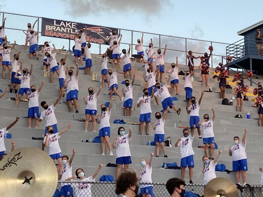 Band members celebrate a first down for Lake Brantley while displaying the newly implemented safety precautions. They stand spaced out in a row with eight feet in between them, and two steps between each line of them.