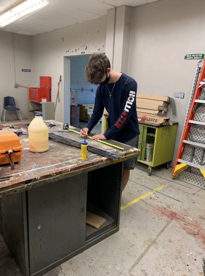 Senior Justin Keyt marks off measurements before the woodshop class lays new flooring. “This project was helpful because it introduced us to flooring,” Keyt said. “It was also special because most projects we do are for other parts of the campus, the new floors are in our shop.”