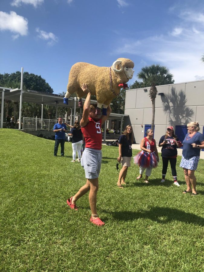 Just outside Patriot Pointe, senior varsity football player Josh Wiles carries a fiber-glass ram over his shoulders. The figure was decked out in Patriot attire in spirit of the big football game against Lake Mary High School, whose mascot is a ram, that happened that night. 