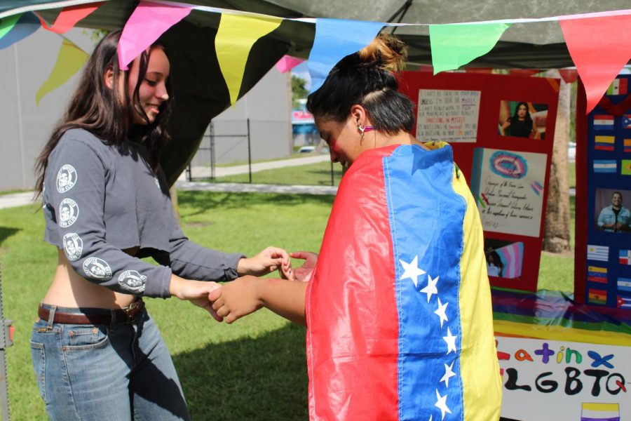 Junior Marcela Maya and sophomore Madalyn Propst dance to bachata at the Gay Straight Alliance tent. The tent represented monumental Hispanic LGBTQ+ figures such as Frida Kahlo.