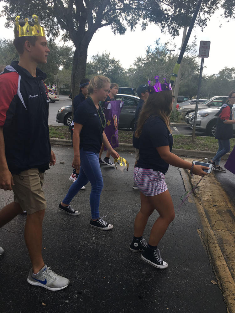 A group of Lake Brantley Rowing Association (LBRA) walk in the homecoming parade. Occasionally tossing the Mardi Gras beads around their neck into the crowd.