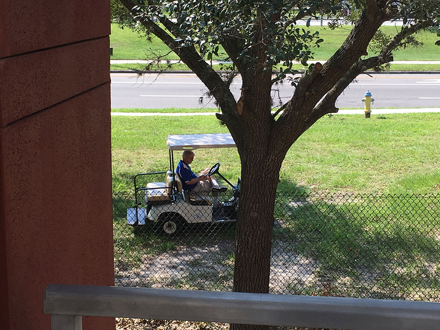 Major Mark Watts sits in a golf cart as he reads his book. Spending time outside while he does not have a class is something he does frequently.