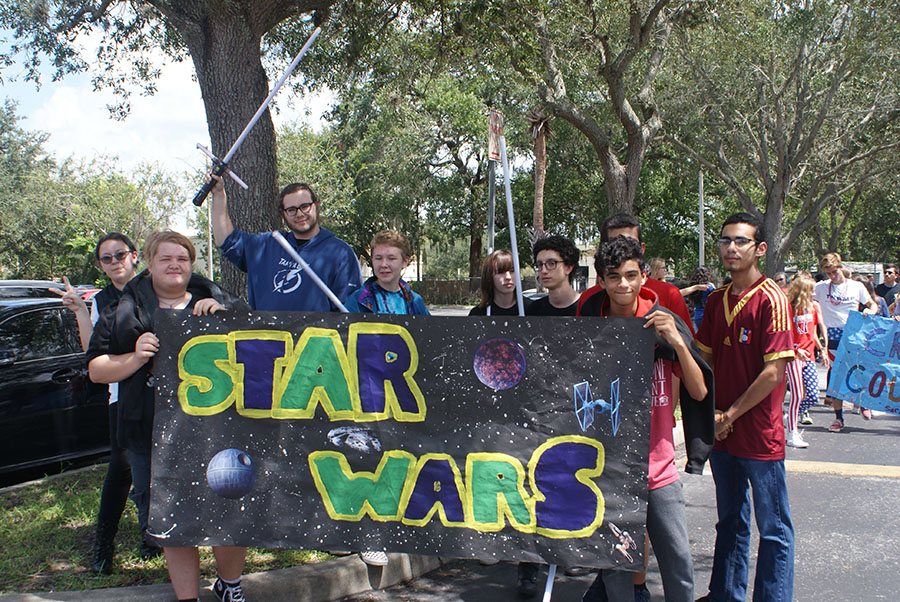 Star Wars Club members pose in the student parking lot with their banners and lightsabers in the air on September 7, the day of the parade. They are excited to walk the route which goes down Sand Lake Road and circles Forest City Elementary School.