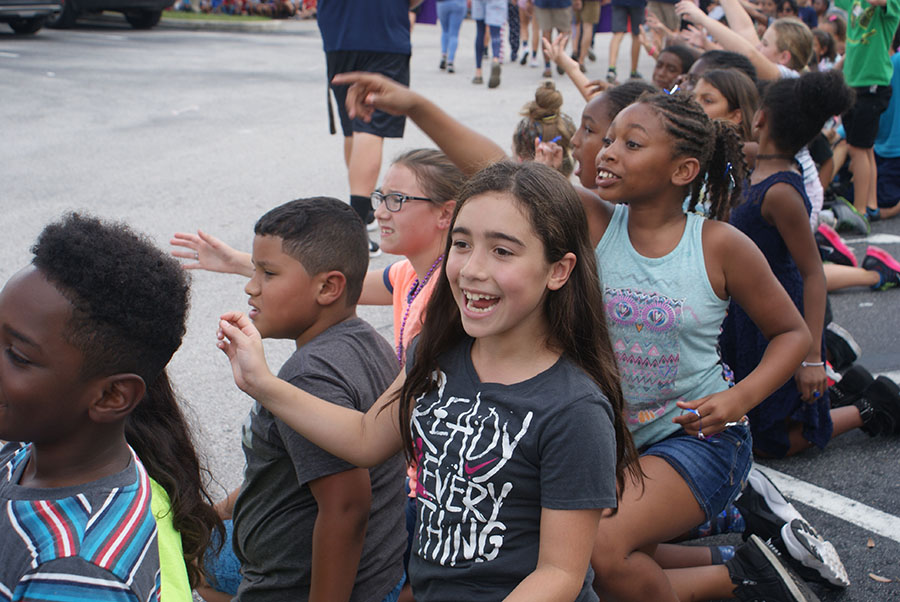 A group of Forest City Elementary School students cheer near the car ramp as the parade floats approach them on September 7, parade day. They reach out to high five participants and to catch the beads being thrown.