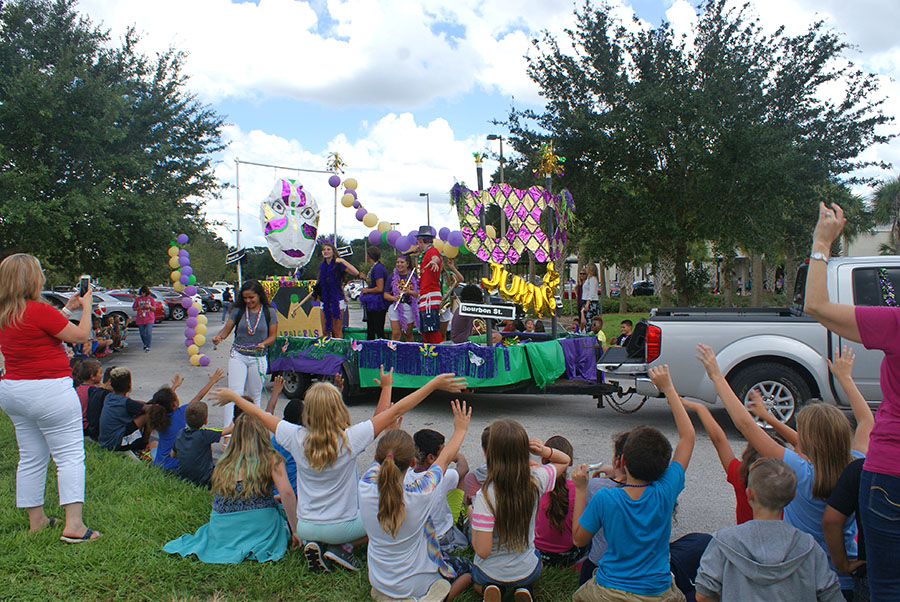Forest City Elementary School kids cheer and wave to get the attention of the junior class float on September 7, parade day. The juniors start throwing beads and playing music as they pass by the students.