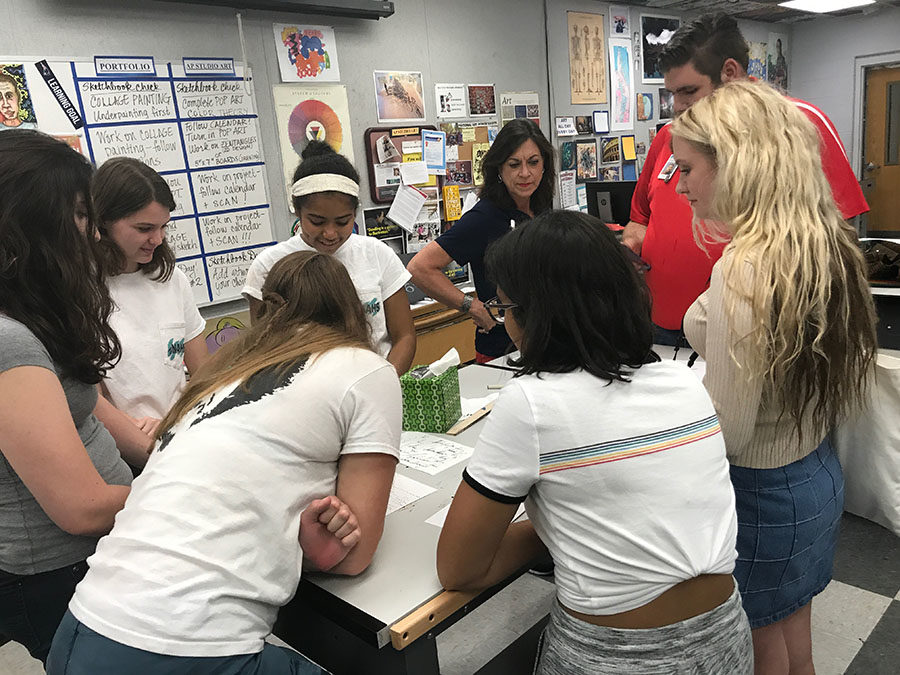  National Art Honor Society members gather around fine arts teachers Katy Farmer and Alex Garver while they discuss the inktober prompts and pieces before them on Friday, Oct.6. Photography teacher Alex Garver asked students to place their works before him so that he could post them on the Lake Brantley fine arts instagram. 
