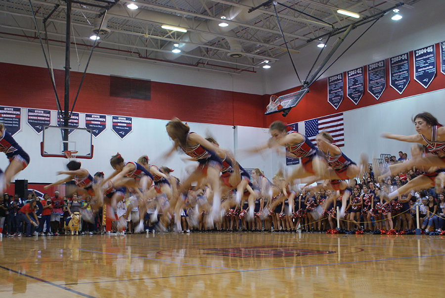 In the main gym on Thursday Sept. 28, the varsity cheerleaders execute a toe touch jump during their performance in the main gym. The cheerleaders timed their performance to the music so that they could jump in unison.