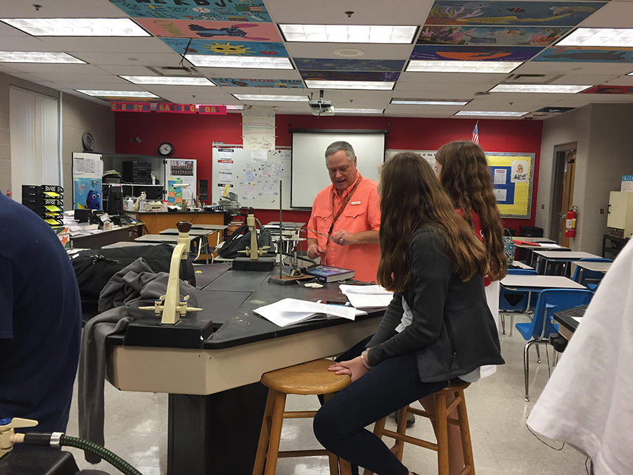 Chemistry teacher David Duffy helps sophomores Emily Klingenberg and Marietta Long to lift up their crucible from the clay triangle during the “Empirical Formula Lab”. The purpose of the lab was to expose students to oxidation techniques involving the careful use of Bunsen burners.