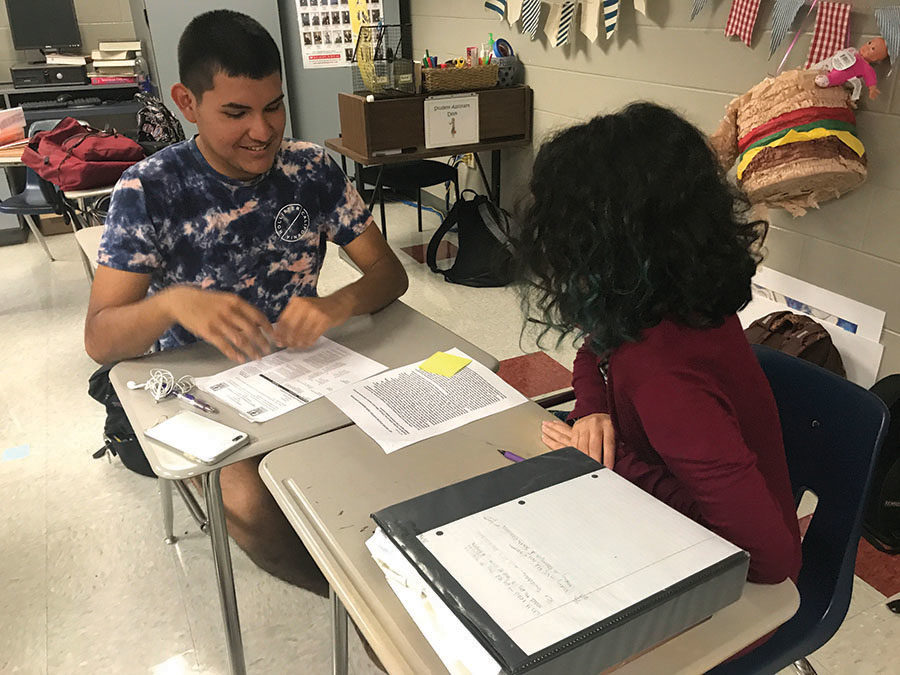 On Monday, May 7, juniors Sebastian Anchea and Veria Puerta-Alvarado discuss the scoring breakdown of an essay in room 8-111 during Advanced Placement [AP] United States History. Vita Simmons, the  AP U.S. history teacher, assigned essays to students in pairs which they scored daily during their review period. She then rewarded students who properly scored the essays with scholastically inspired prizes. “The essays helped us understand why students got certain scores that they did.  It also made it easier to recognize context and analysis. The essays were good review on [the] topics too since the evidence students used would refresh our own memories,” Puerta-Alvarado said. 

