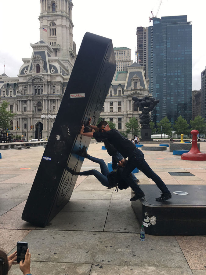 In a cooperative effort, junior Logan Turner, junior Mackenzie Walton, and sophomore Mason Walton, struggle to keep this domino from falling in front of the Municipal Services Building. In the background, the intricate architecture of the Philadelphia City Hall sticks out.