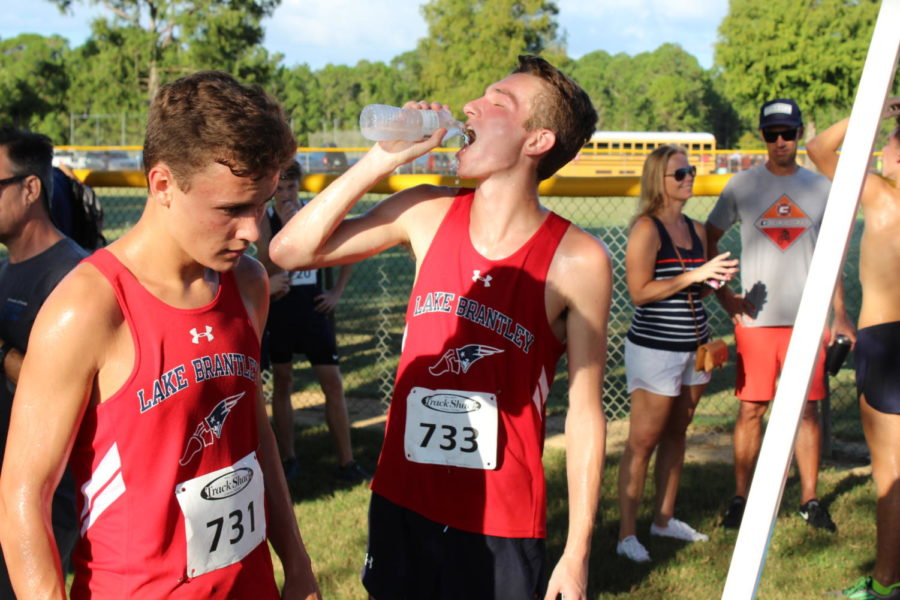 Seniors and varsity cross country runners Zion Van der Sanden and Trent Shackelford take a water break after running in the Sept. 1 Deland Invitational. The boys varsity team placed fifth at the meet. 
