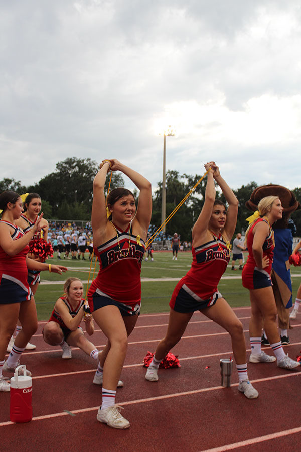 Varsity cheerleaders, Cecilia Dequatro, Josalyn Pagan and Lexi Kreimier take their positions and use a catapult  to launch a t-shirt into the crowd. The “Yellow Out” football game against Hagerty High School took place on Friday, Aug. 24 on Tom Storey Field, with the Patriots winning with a score of 35-17. 

