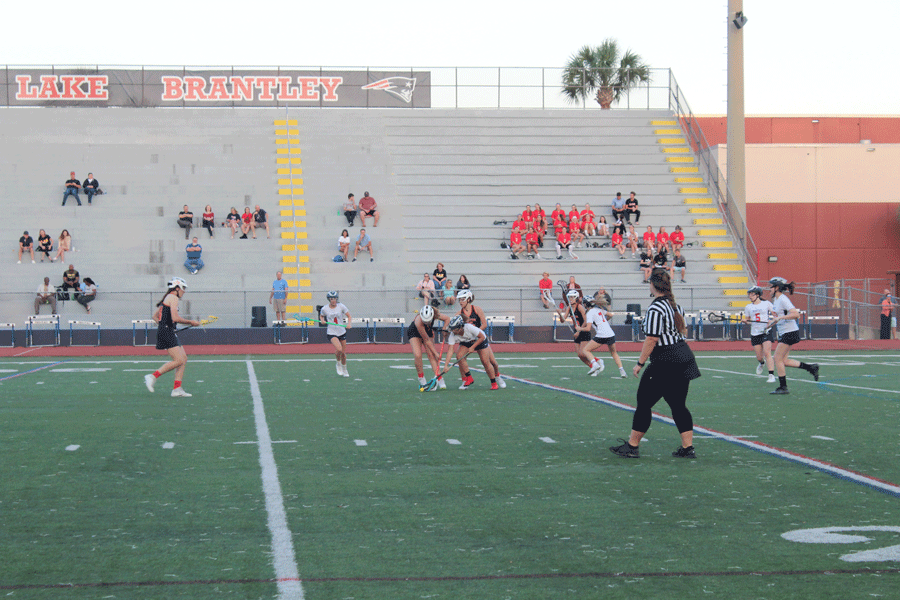Junior varsity players go head to head for the ball as they approach Brantley’s side of the field during the game on on Monday, March 4. The junior varsity and varsity girls lacrosse teams played against Winter Park High School in Darwin Boothe Stadium with the junior varsity team winning at 10-4 and the varsity team losing at 8-10.