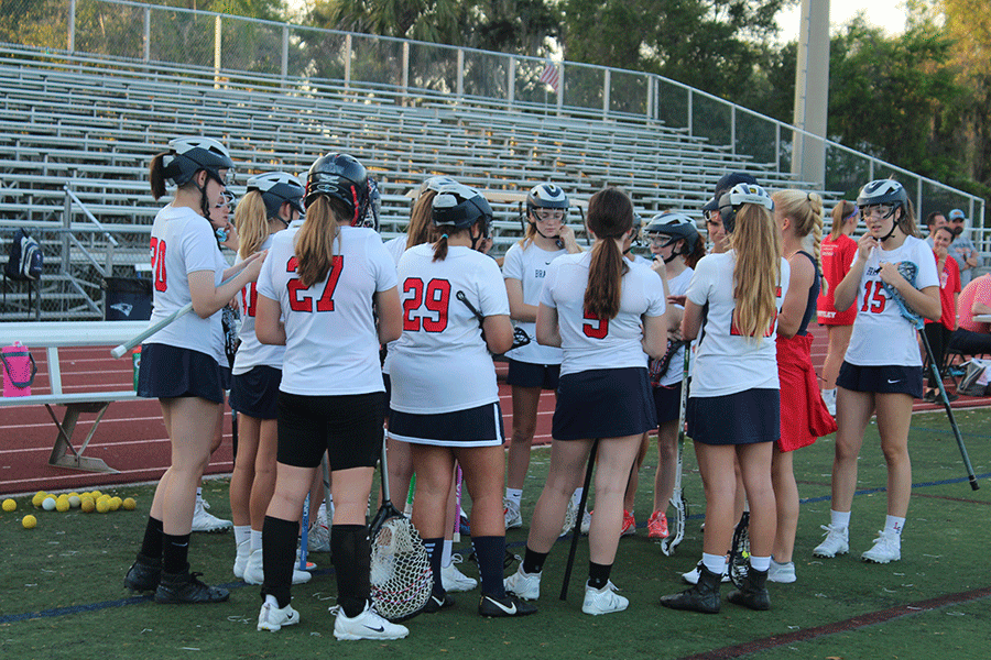 Junior varsity players huddle together before their game on Monday, March 4, to encourage and motivate one another. The junior varsity and varsity girls lacrosse teams played against Winter Park High School in Darwin Boothe Stadium with the junior varsity team winning at 10-4 and the varsity team losing at 8-10. “The team and coaches are my favorite thing because it’s like a second family,” junior and JV player Allison Roosenberg said. “Everyone gets along and there’s no drama.” 