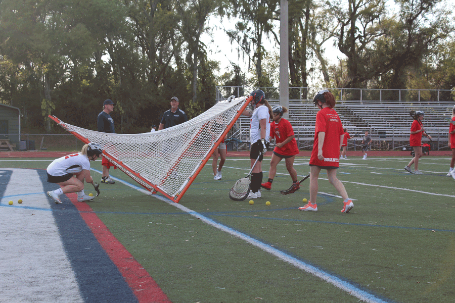 The girls work together to practice passing and retrieving the balls before their game begins on Monday, March 4. The junior varsity and varsity girls lacrosse teams played against Winter Park High School in Darwin Boothe Stadium with the junior varsity team winning at 10-4 and the varsity team losing at 8-10.