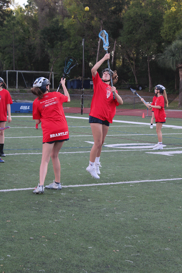 Senior and junior varsity player Lauren Bruce jumps to catch the ball following the practice of a draw with another team member on on Monday, March 4. The junior varsity and varsity girls lacrosse teams played against Winter Park High School in Darwin Boothe Stadium with the junior varsity team winning at 10-4 and the varsity team losing at 8-10. 