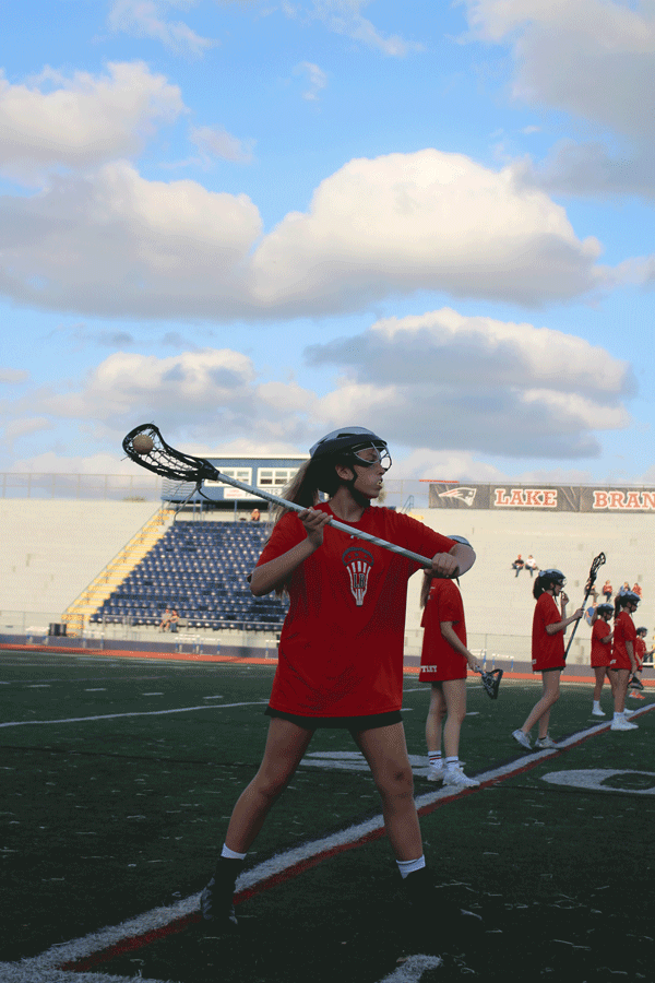 The junior varsity team begins their warm-up by practicing passing, shooting, and ground balls on Monday, March 4 . The junior varsity and varsity girls lacrosse teams played against Winter Park High School in Darwin Boothe Stadium with the junior varsity team winning at 10-4 and the varsity team losing at 8-10. “I love winning any game really, especially with the wonderful team I have,” junior and JV player Riley Fleming said. 
