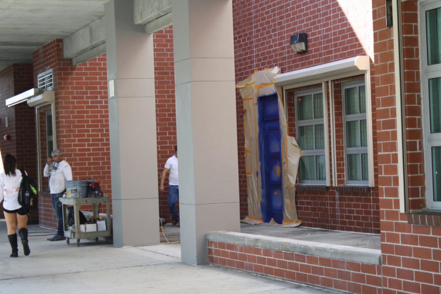 The staff hired to paint the school puts finishing touches on the now blue doors. Columns and the exterior of the building are also being repainted a steel grey color.
