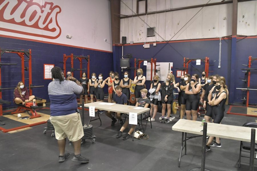 Coach David Rollins speaks to the girls’ weightlifting team during their meet against Lake Mary High School on Wednesday, Nov. 11. The events at the meet were the bench press and the clean and jerk. While the girls lost with a score of 19-52, it was a successful season with senior Crista Helm moving on to the state finals.