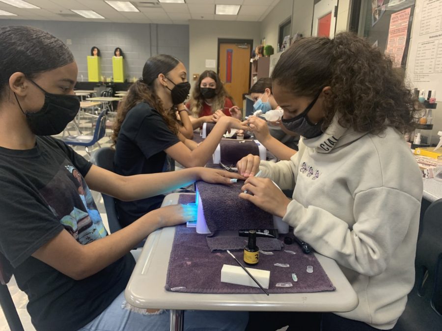 Students from the first period Cosmetology class give each other manicures. They are practicing with acrylic nail tips and gel polish.