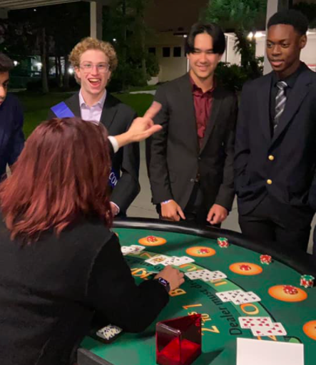 Seniors Kade Sowers, Sebastian Kee and Miles Butterfield take advantage of the gambling tables provided as entertainment during the Homecoming dance on Nov. 6. Each table featured a different casino card game to match the Fabulous Lake Brantley theme.