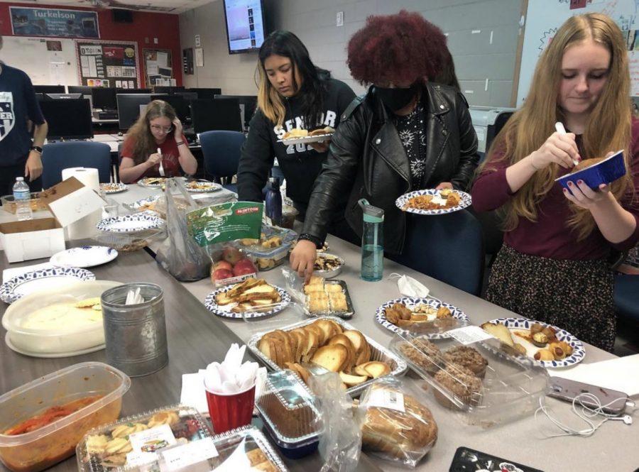 Students in Katie Turkelson's 5th period make their way around a table of dishes, buffet style, and prepare to share about their represented culture on Oct. 27. “It's very nice to know that there are people from your own country, like where you’re from, in the school because you know that you’re not alone and that you’re not the only person who is going through the changes of coming from a different country.
