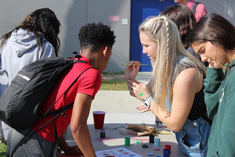 Senior Joya Ogier paints sophomore Hasani Crichton’s face at the Winter Festival on Dec. 10. The Student Government set up popcorn stands and activity booths, providing activities like face painting and cookie decorating. 