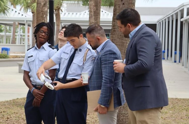 Cadets+senior+Jahi+Abbott+and+junior+Deven+Fraser+along+with+Congressman+Cory+Mills+and+principal+Brian+Blasewitz+check+the+controls+of++the+Parrot+AI+drone+in+flight.